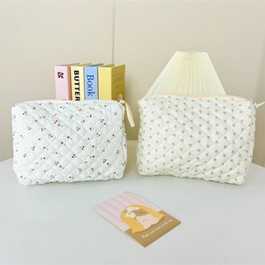 Close-up of quilted cotton cosmetic bags with cherry and floral prints with zip closure
