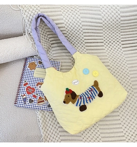 Detail of yellow quilted tote bag featuring a cute puppy embroidery and purple handles