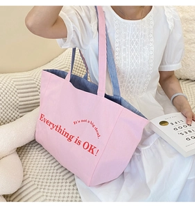 Detail der rosa Canvas-Tasche mit rotem Textdruck und blau gestreiftem Innenfutter