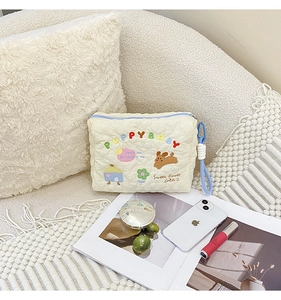 Detailed embroidery on a quilted cream makeup bag featuring cute puppy and flower motifs