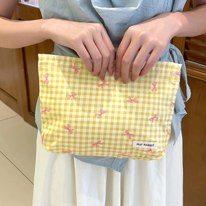 Dettaglio della trousse gialla a scacchi con fiocchi rosa ed etichetta del marchio