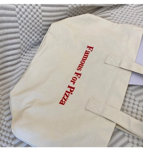Detail einer großen cremefarbenen Canvas-Tasche mit rotem Famous For Pizza Vintage-Aufdruck