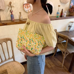 Detail of yellow floral tulip makeup bag with fabric label on a casual summer outfit