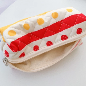 Detailed macro view of quilted floral pencil case with yellow polka dots and red stripes