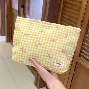 Dettaglio della borsa cosmetica a quadretti gialli con fiocchi rosa ed etichetta