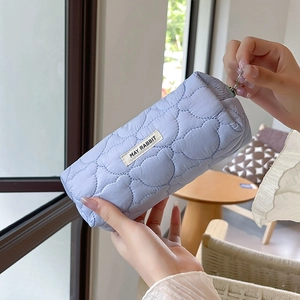 Detail of light blue quilted pencil case with heart stitching held by a hand