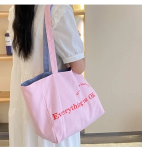 Detail der rosa Segeltuchtasche mit rotem Textdruck und blau gestreiftem Innenfutter
