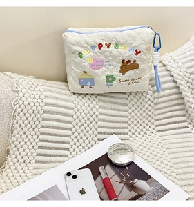 Detail of white quilted makeup bag featuring cute puppy and floral embroidery