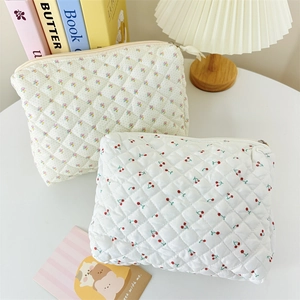 Detailed close-up of quilted floral and cherry print cosmetic bags on a white desk