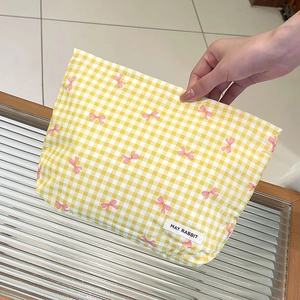 Dettaglio della trousse a scacchi gialli con fiocchi rosa ed etichetta del marchio