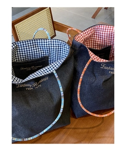 Dettaglio della borsa denim con fodera a quadri rossi, ricamo e manici intrecciati