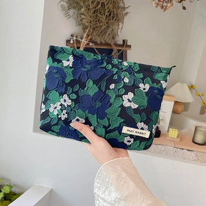 Detail of blue floral embossed jacquard makeup bag with May Rabbit label in hand