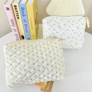Quilted floral and cherry print cotton cosmetic bags with zip closure on a white table