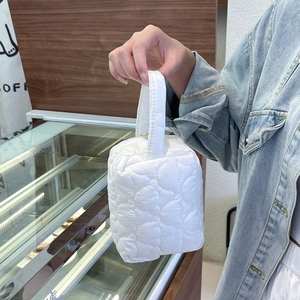 Sac cube blanc matelassé avec motifs de cœurs présenté dans un décor de café