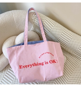 Nahaufnahme der rosa Canvas-Einkaufstasche mit rotem Text und blau gestreiftem Innenfutter