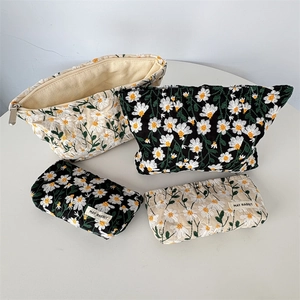 Set of four daisy embroidered makeup bags in black and beige with detailed floral patterns