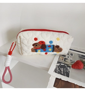 Detail of white heart-quilted puppy makeup bag with red zipper and hook clip