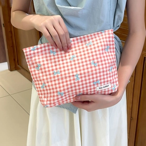 Dettaglio della borsa da toilette a quadretti rossi con stampe di fiocchi blu