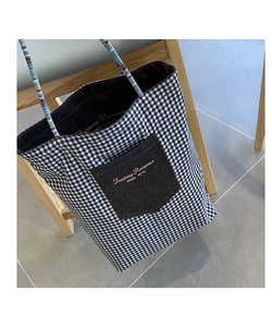 Dettaglio della tasca frontale in denim con ricamo dorato su borsa tote a scacchi blu