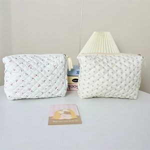Detail of quilted cotton makeup bags featuring cherry and floral patterns with zippers