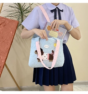 Close-up of quilted light blue shoulder bag featuring cute dog patch and pink strap