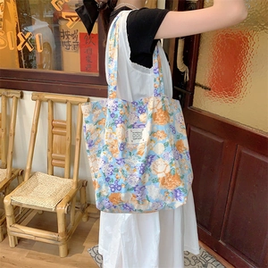 Sac fourre-tout en toile à fleurs avec motifs bleus et patch LOVE porté à l'épaule