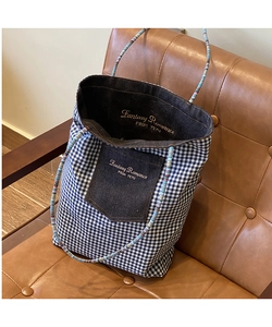Dettaglio borsa tote in tela a quadretti blu con tasca in denim e manici in corda intrecciata