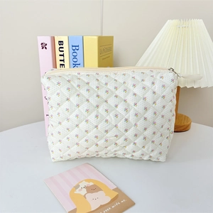 Detail of cream quilted makeup bag with floral print and soft fabric texture closeup