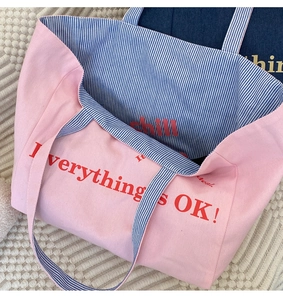 Detail der rosa Canvas-Tasche mit blau gestreiftem Futter und Grafik-Print