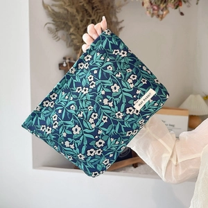 Close-up of floral jacquard makeup bag with white flower patterns and brand tag