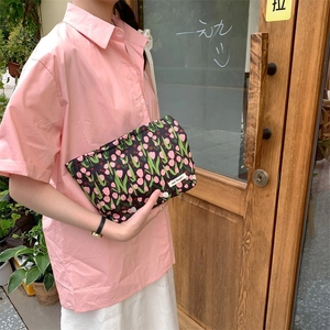 Floral makeup bag with pink tulips held by a woman in a casual floral dress lifestyle scene