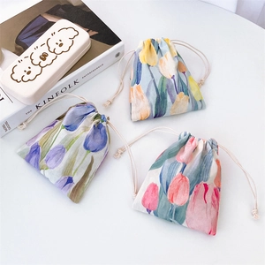 Floral drawstring pouches with tulip patterns and cute cartoon storage box on a desk