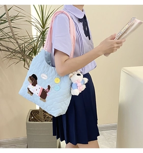 Close-up of quilted light blue tote bag featuring cute dog embroidery and a bear charm