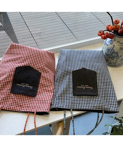 Dettaglio di borse tote a quadretti rossi e blu con tasca in denim e ricamo curato