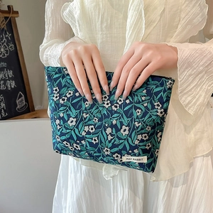 Floral makeup bag with blue leaf pattern and zipper closure held by a person