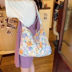 Detailed shot of floral canvas tote bag with orange and lilac patterns in a cozy cafe