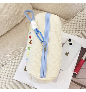 Detail of quilted heart texture and colorful embroidery on cream storage bag