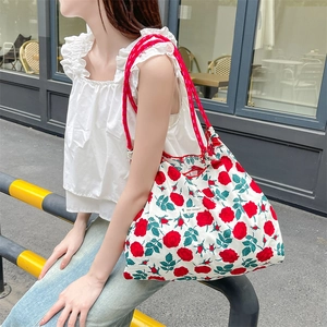 Dettaglio della borsa shopper a fiori con rose rosse e manici in corda intrecciata