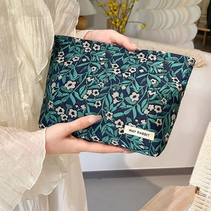 Close-up of jacquard floral makeup bag with green leaves pattern and brand label