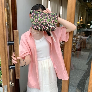Floral makeup bag with tulip patterns held by model against a wooden background
