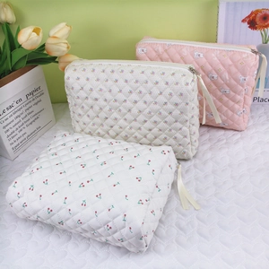 Detailed close-up of quilted floral, cherry, and bear pattern makeup bags with metal zippers
