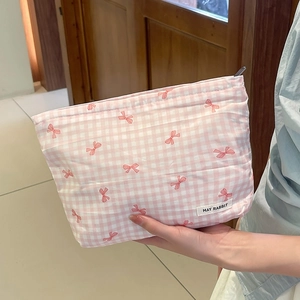 Dettaglio della trousse a quadretti rosa con motivi a fiocco rosso e etichetta logo
