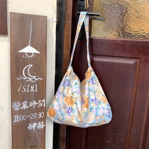 Detail of floral canvas tote bag hanging on a vintage wooden door in a street shop setting