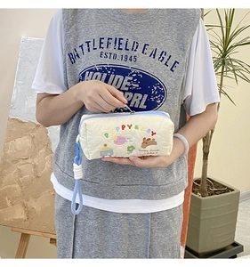 Detail of white quilted storage bag with colorful PuppyBaby embroidery and wrist strap