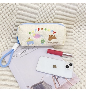 Detailed embroidery of colorful PuppyBaby text and dog patterns on quilted makeup bag