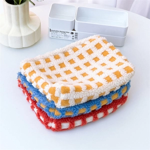 Three-piece checkered plush storage organizers in yellow, blue and red on a white table