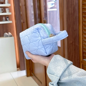 Gros plan d'une trousse de maquillage matelassée bleu clair avec détail de zip doré