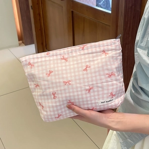 Pochette trucchi a scacchi rosa con stampa a fiocco e cerniera tenuta in mano