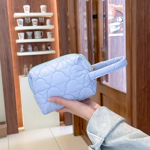 Détail du sac en nylon matelassé bleu clair avec coutures nuage et zip doré