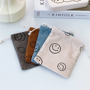 Detailed texture of smiley corduroy drawstring bags in muted colors with Kinfolk props